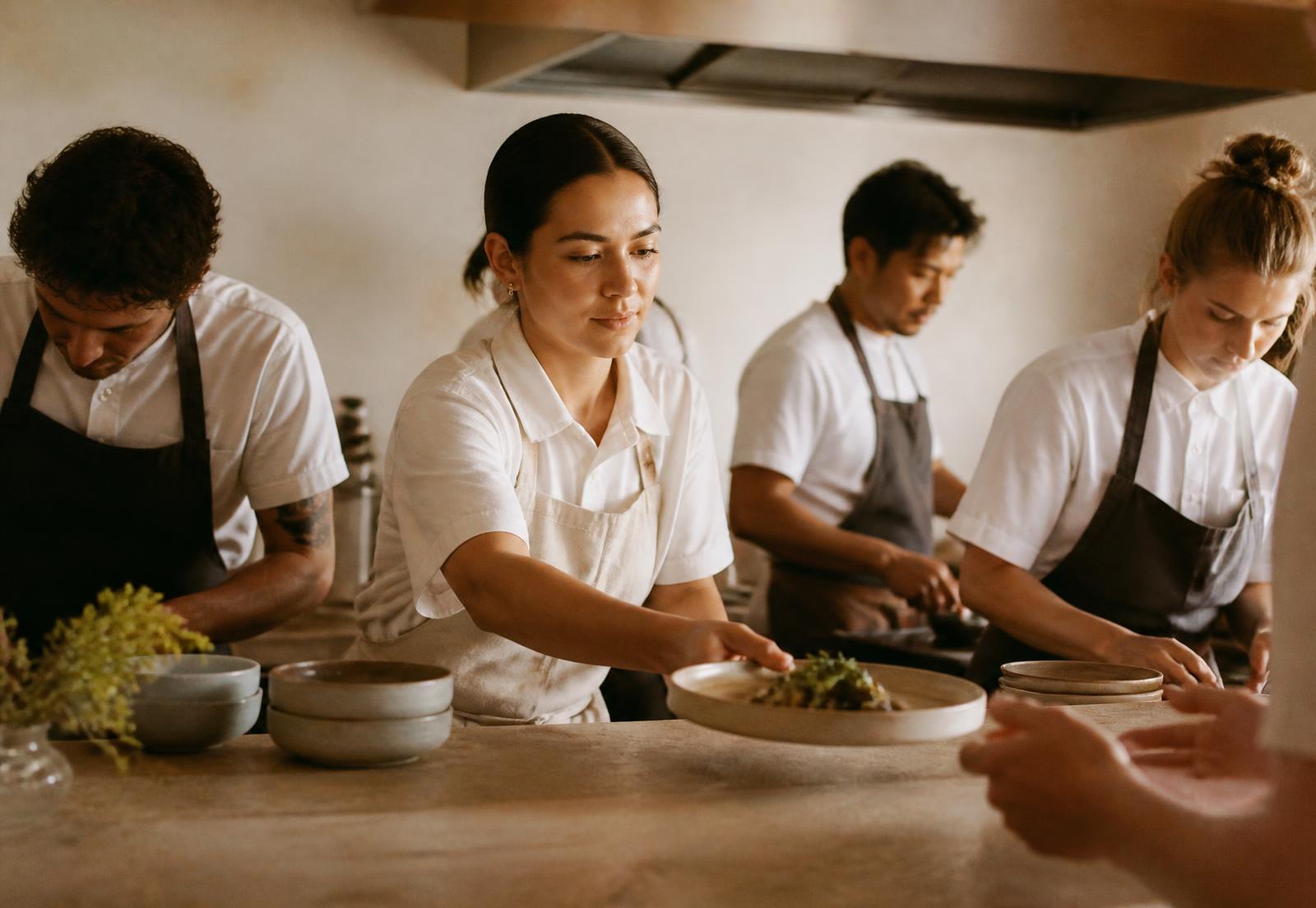 A kitchen team working together at a service pass, each person focused on their own role